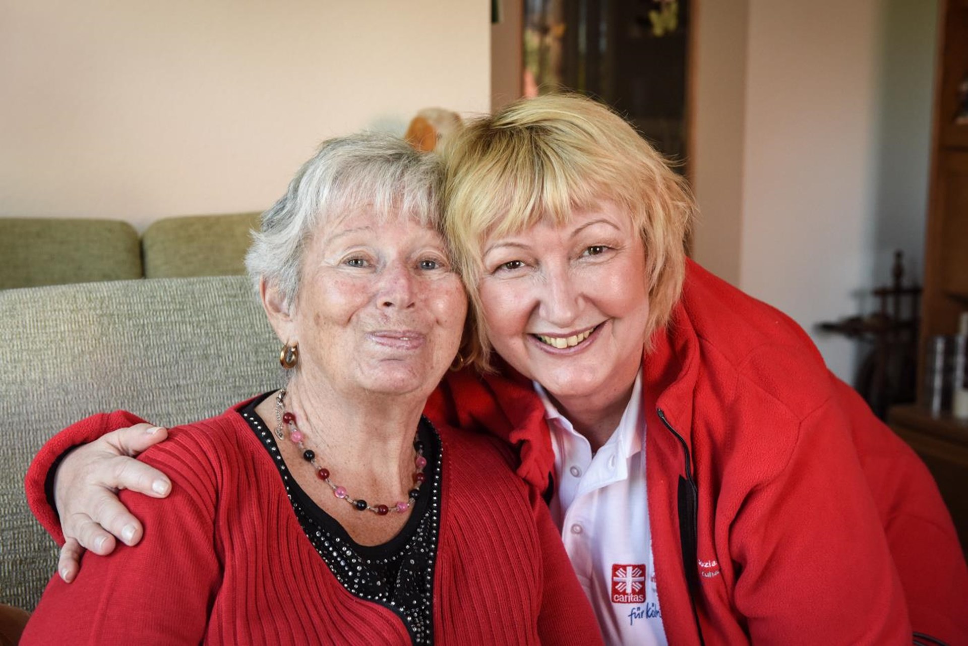 Pflegerin und Seniorin Arm in Arm
